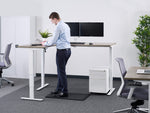 man working at a standing corner desk in an office