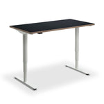 a modern, adjustable standing desk with a black top surface and white legs.