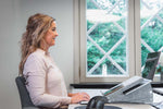 Woman at a desk using Ergo-Top 320 Circular Laptop Stand smiling.