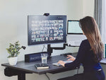 Woman using Bakker Elkhuizen Filex Galaxy Single Monitor Arm at desk.