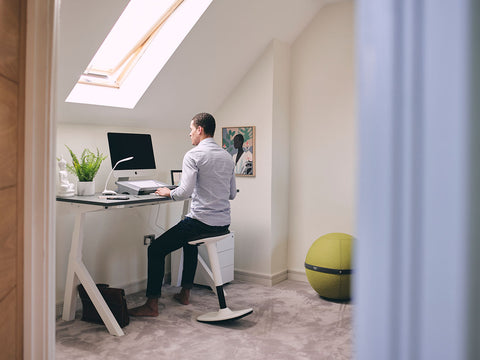 man using white ergonomic desk stool at desk