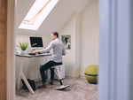 man using ergonomic desk stool in home office