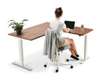 woman sat on a chair working on her laptop on a corner adjustable desk